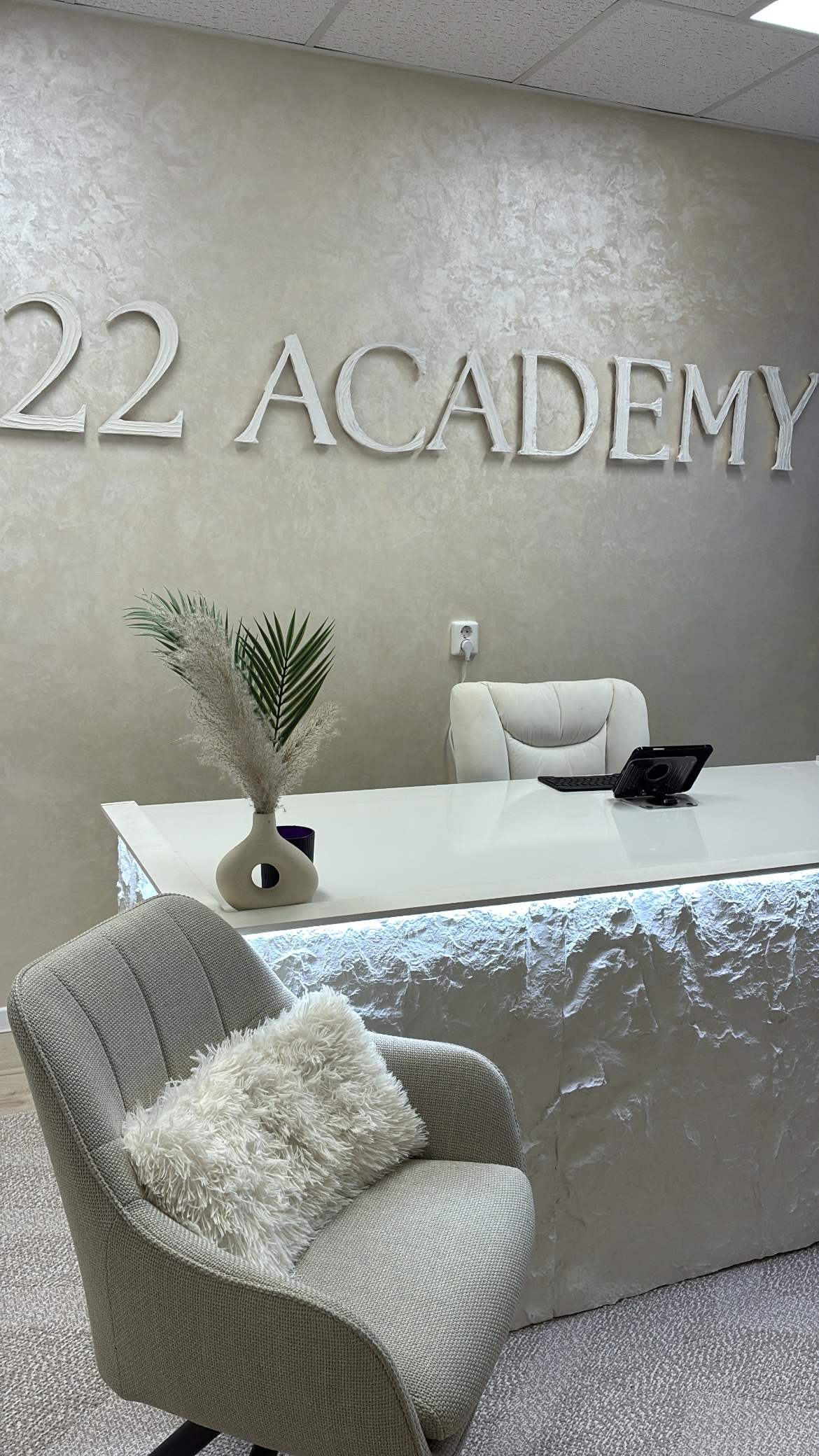 Ontvangstbalie met de letters 22 Academy op de muur en een fauteuil