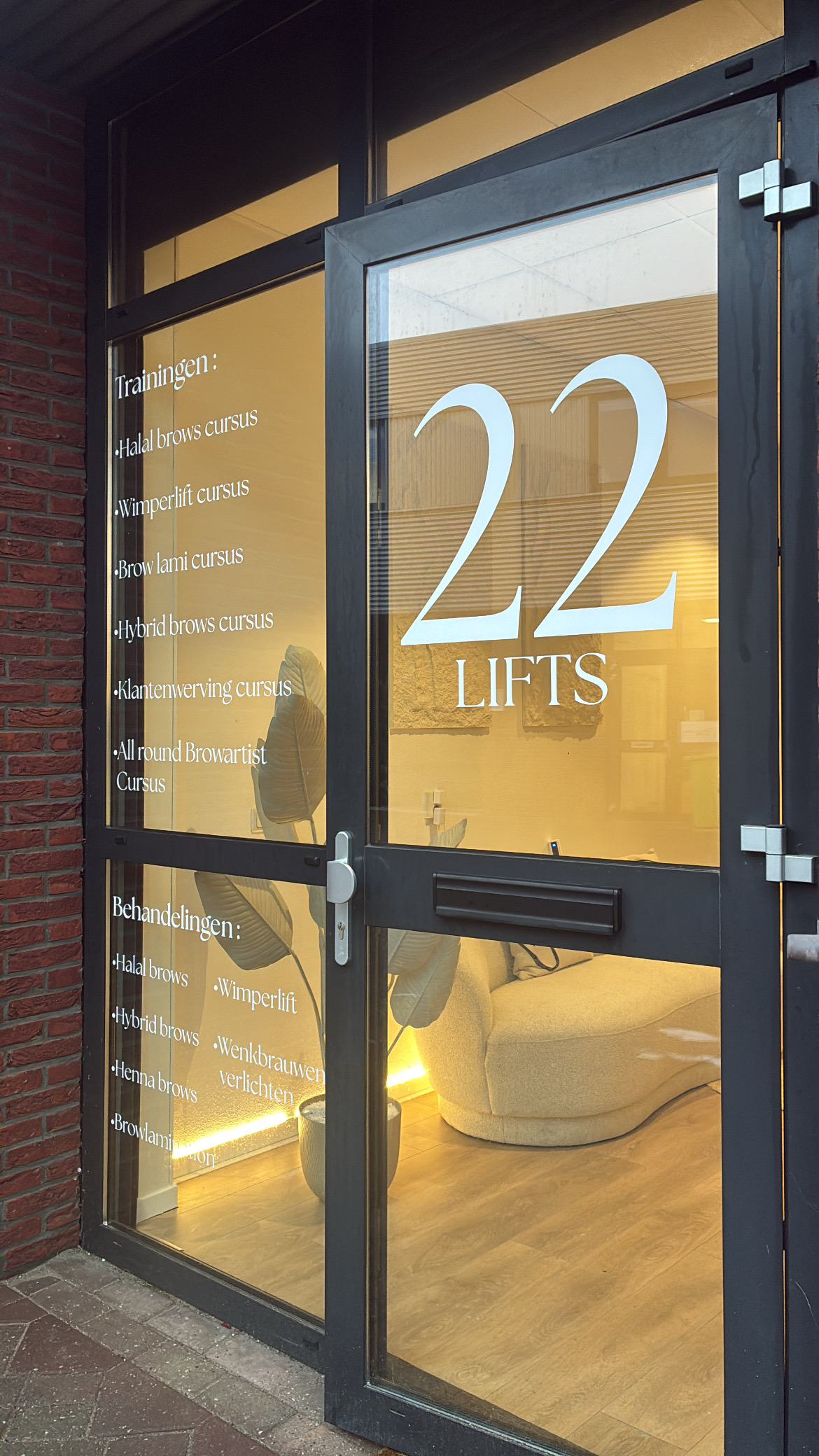 Glazen voordeur van 22Lifts met het 22 Lifts-logo en de lijst met trainingen op het glas