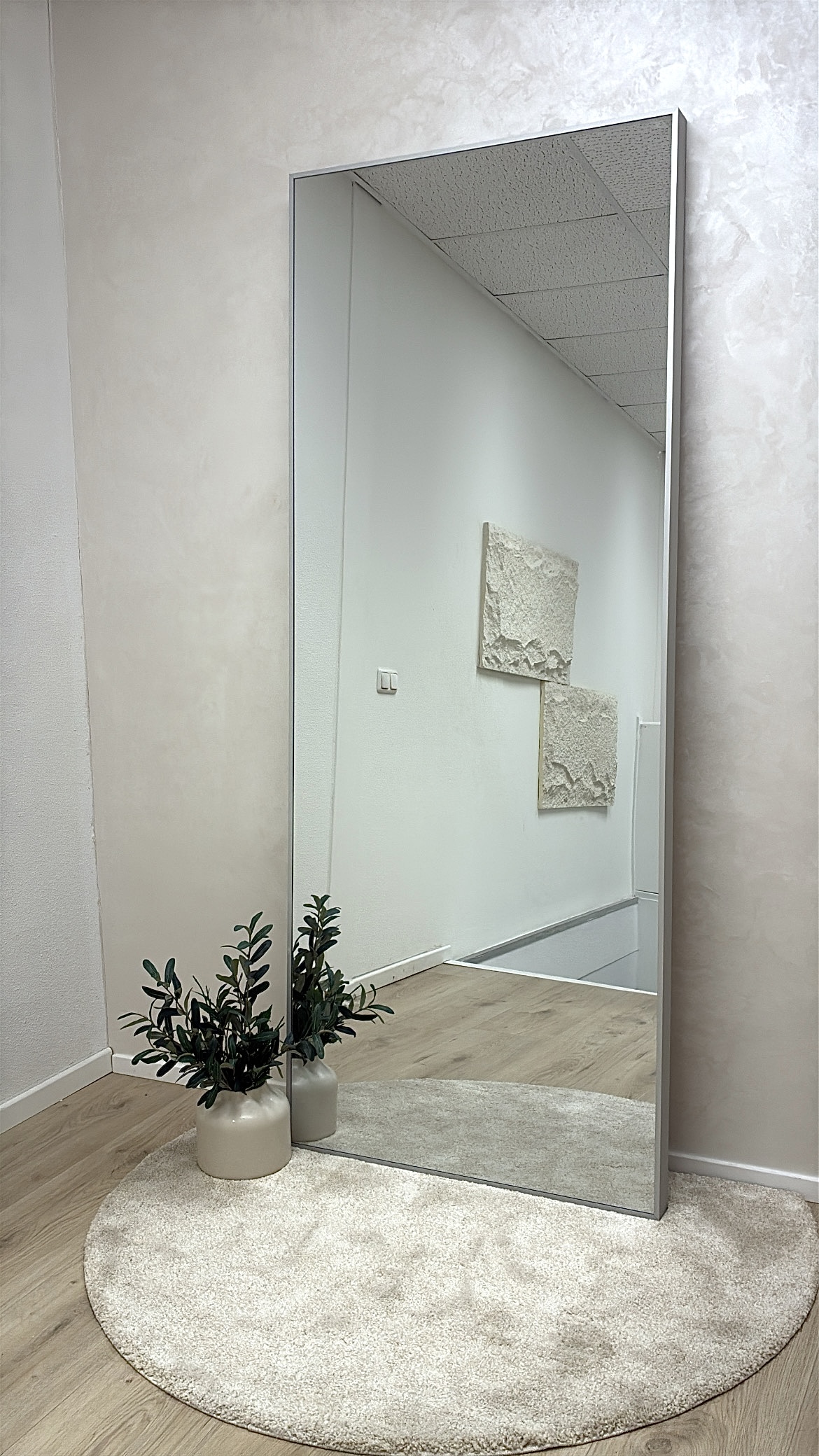 Grote passpiegel op een rond kleed met planten